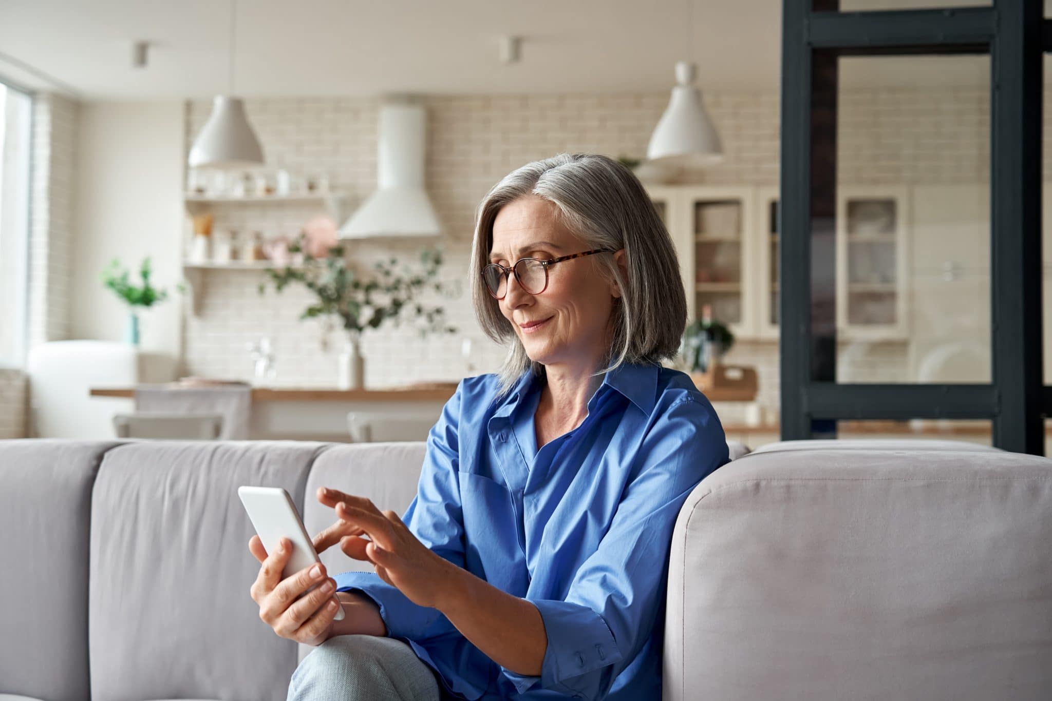 Femme consultant son smartphone sur son canapé